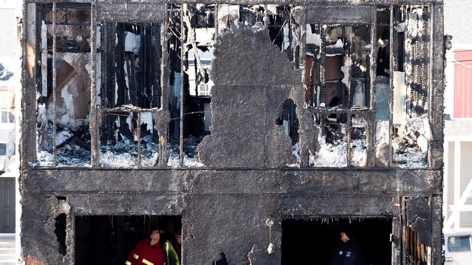 Des enquêteurs dans un bâtiment presque complètement détruit par le feu.