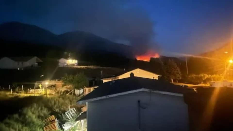Quelques bâtiments à l'avant-plan avec un feu au loin.