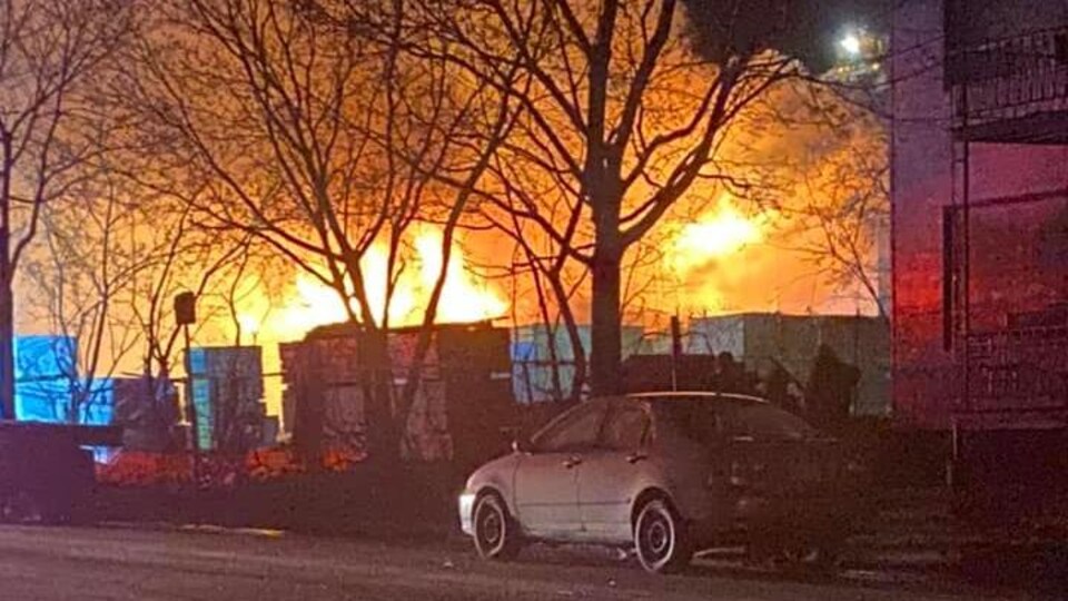Des flammes devant une auto dans la rue.