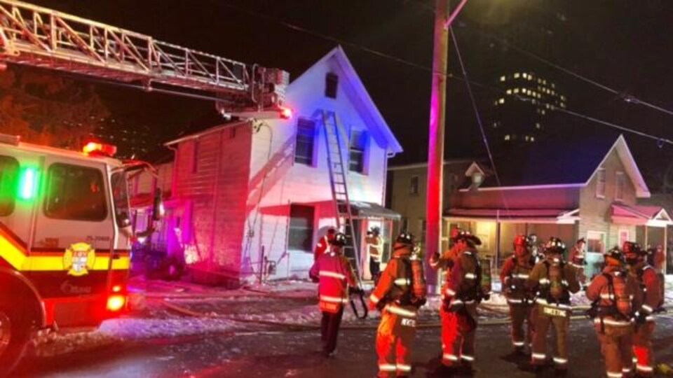 Une dizaine de pompiers près d'un camion-échelle.