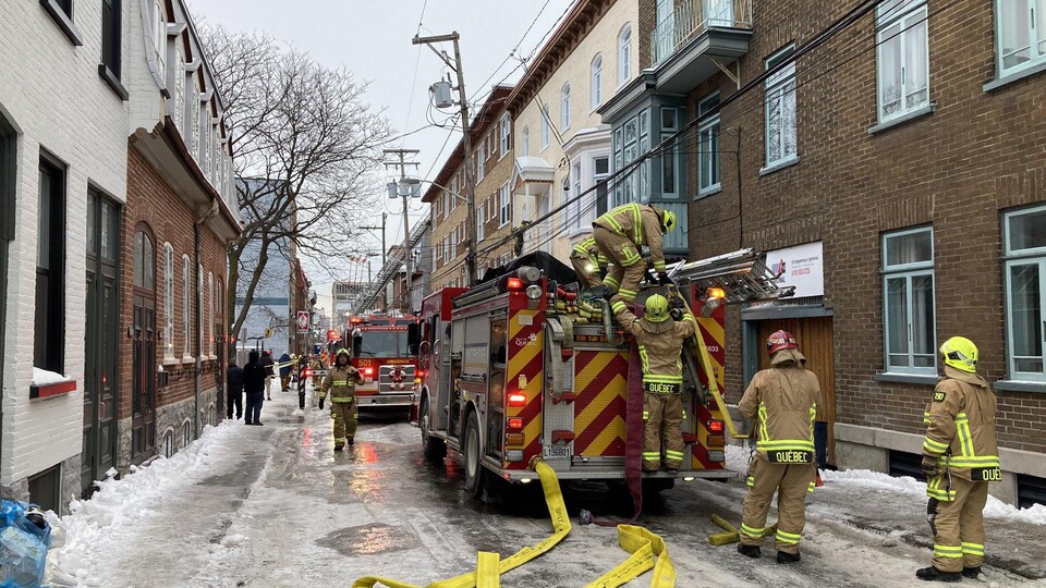 Plusieurs pompiers combattent un incendie.
