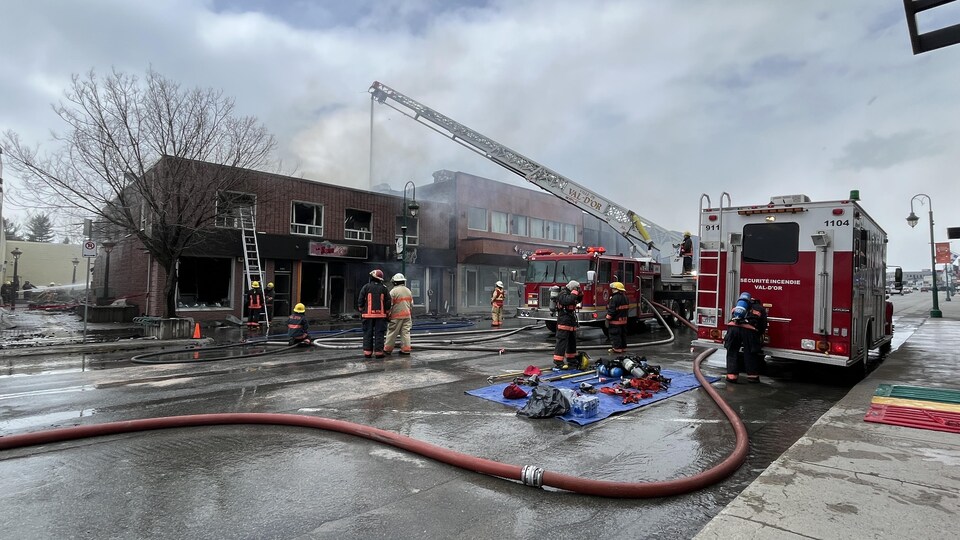 Des pompiers devant un immeuble en feu à Val-d'Or avec beaucoup de fumée.