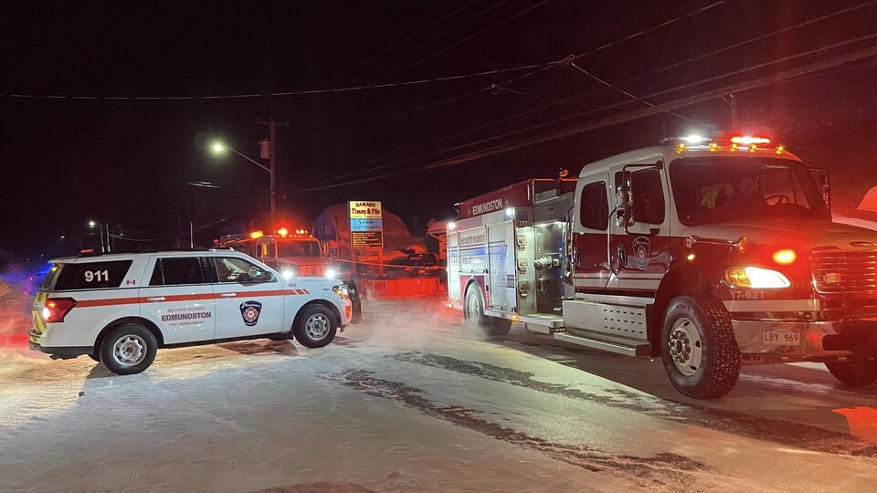 Une voiture de la sécurité incendie et un camion de pompiers garés sur une route de nuit.