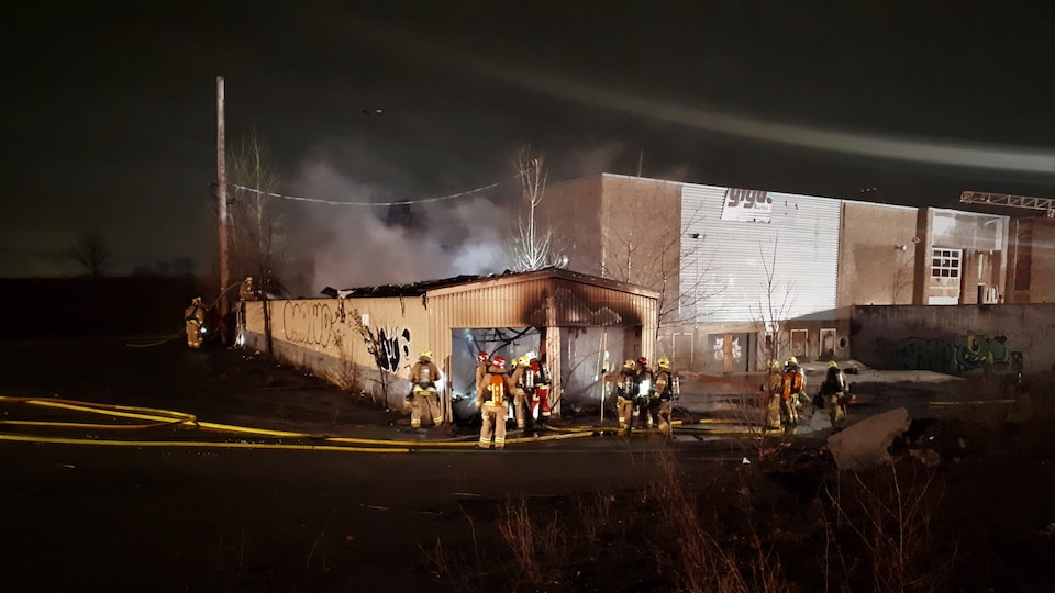 Des pompiers devant un bâtiment en flammes.