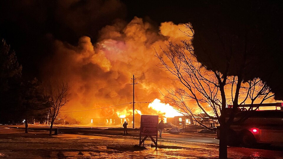 Des flammes engloutissent un hangar.