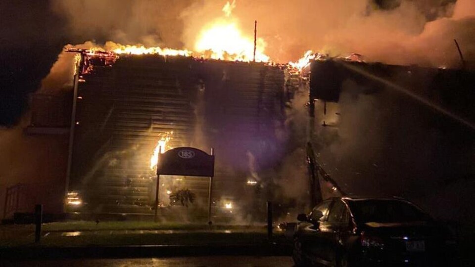 Les flammes s'échappent du bâtiment pendant la nuit.