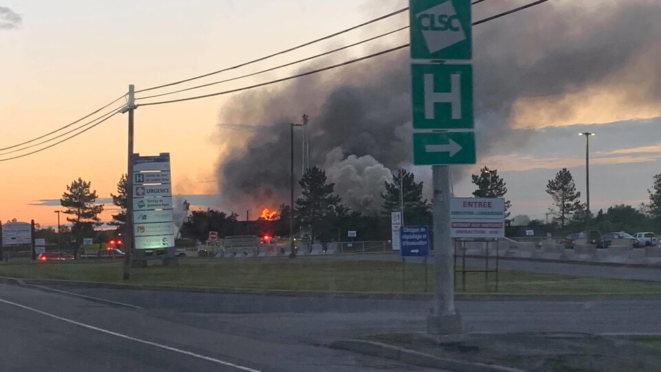 Les flammes sortent de la bâtisse abritant une clinique médicale. La fumée monte très haut dans le ciel.