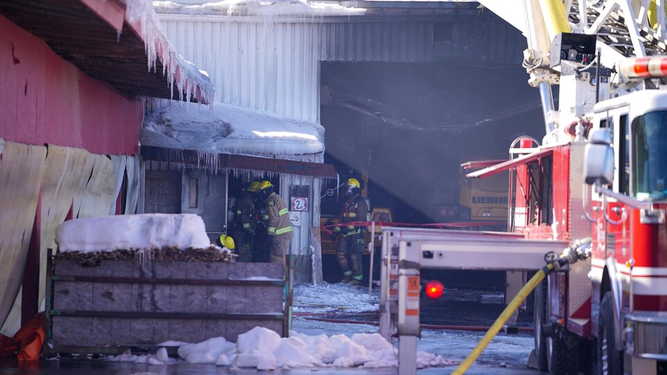 Des pompiers à l'oeuvre dans un bâtiment d'entreprise brûlé en hiver.