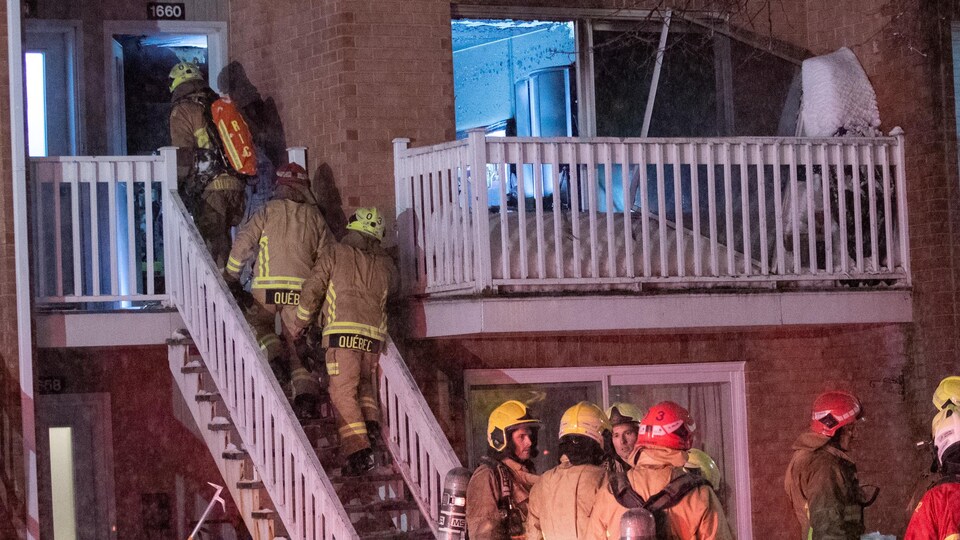 Des pompiers s'engagent dans une maison en feu.