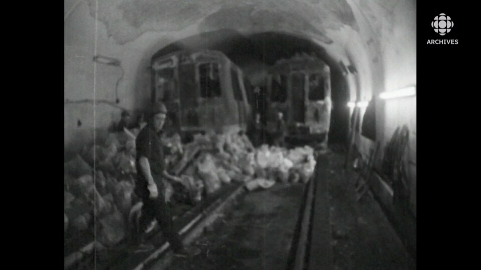 Des wagons calcinés et des hommes qui traversent les rails de métro.