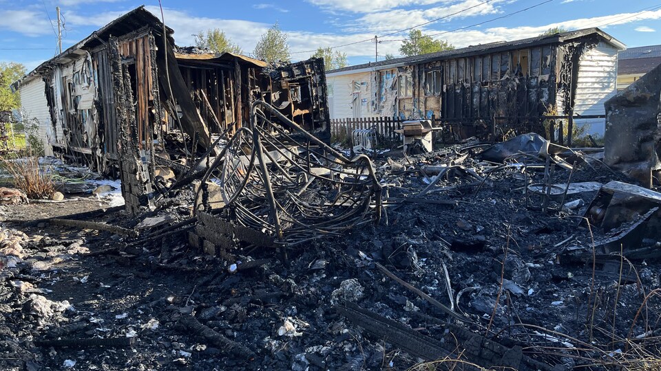 Les restants d'une maison et des cendres à la suite d'un incendie.