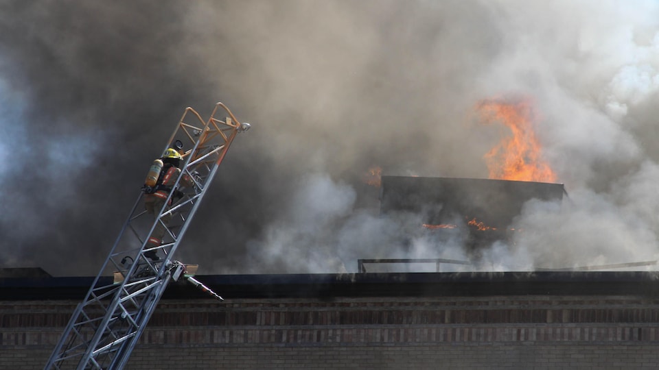 Un pompier sur une échelle tente d'éteindre un incendie.