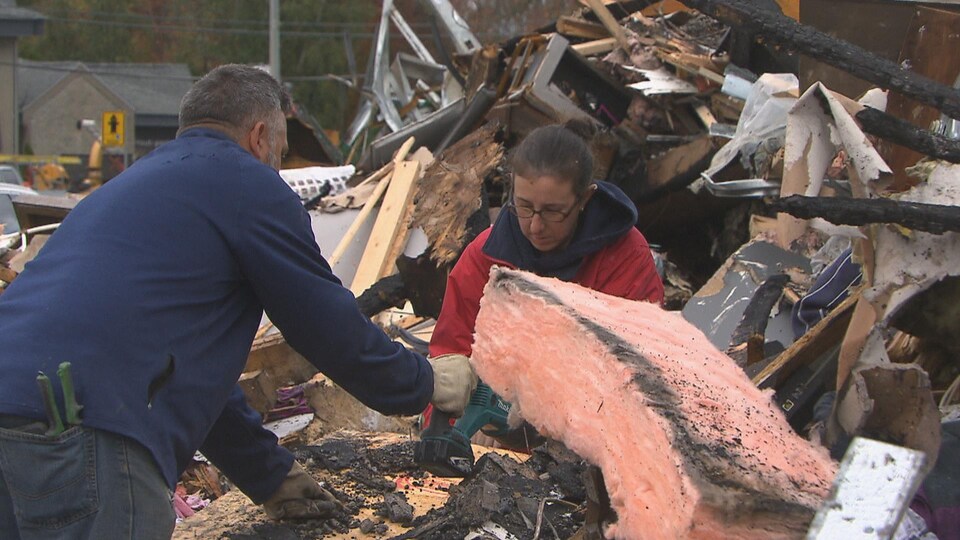 Un homme et une femme recherchent des biens intacts parmi les débris d'un incendie.