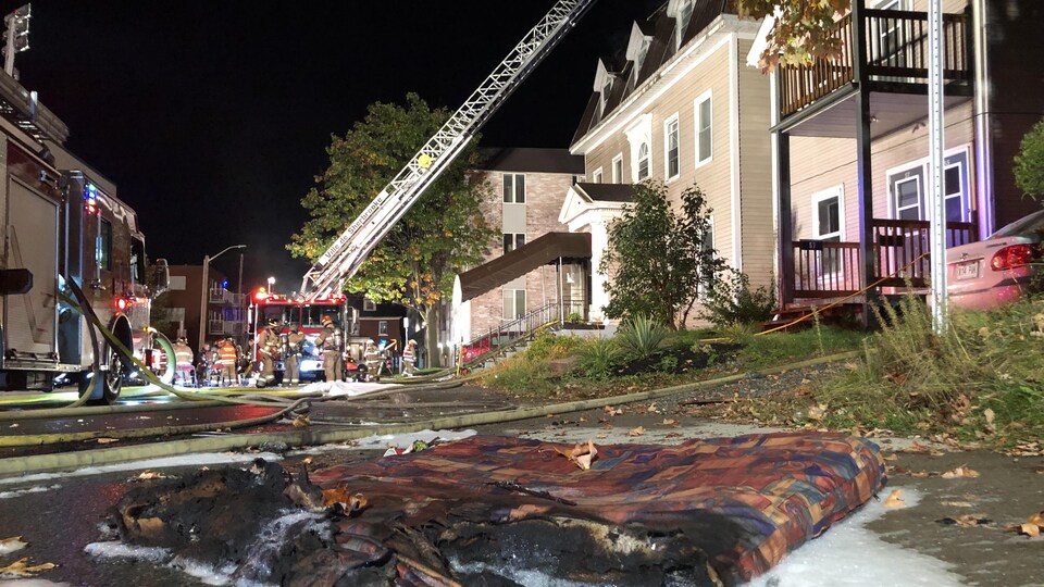 Des camions de pompiers devant une résidence en flammes. 