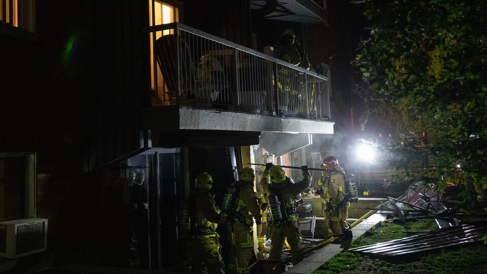 Des pompiers, la nuit, interviennent sur une scène d'incendie.