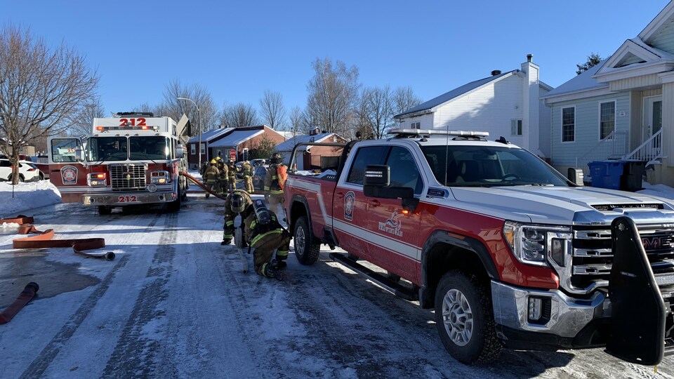 Des camions de pompiers et des pompiers dans une rue enneigée.