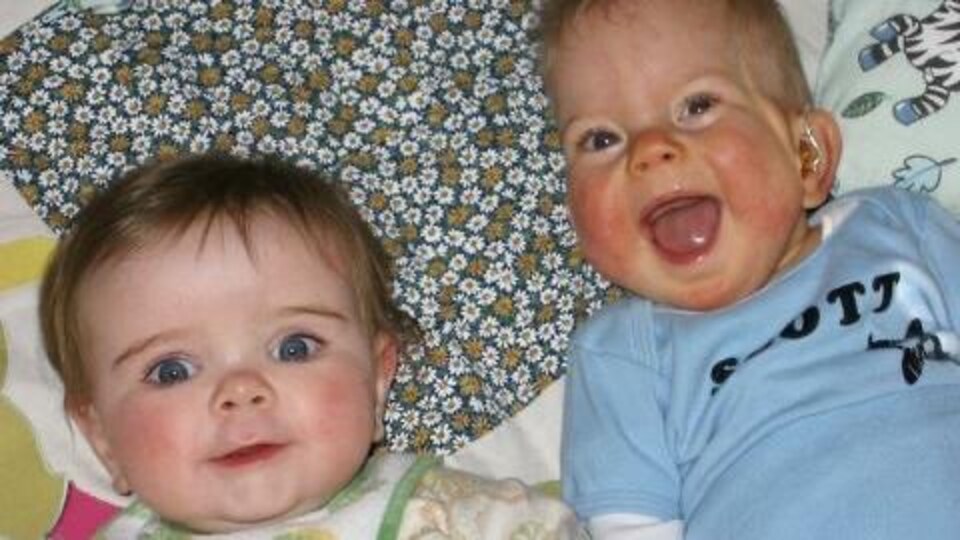 Deux bébés souriants allongés ensemble.