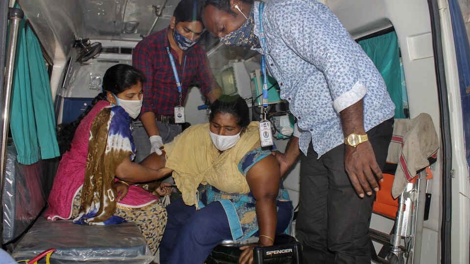 Un patient est aidé par d'autres personnes à descendre d'une ambulance à l'hôpital gouvernemental d'Eluru, en Inde.