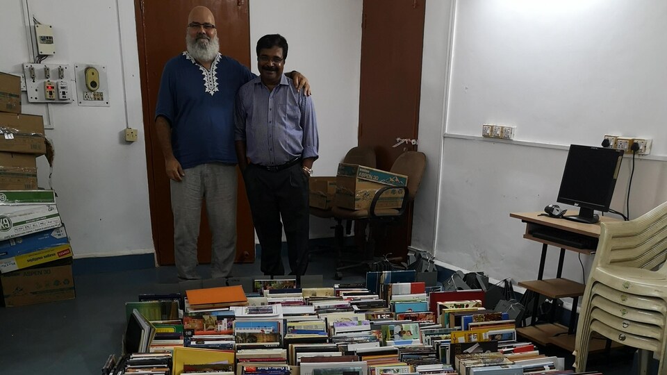Carlos Bergeron et un professeur devant les milliers de livres.