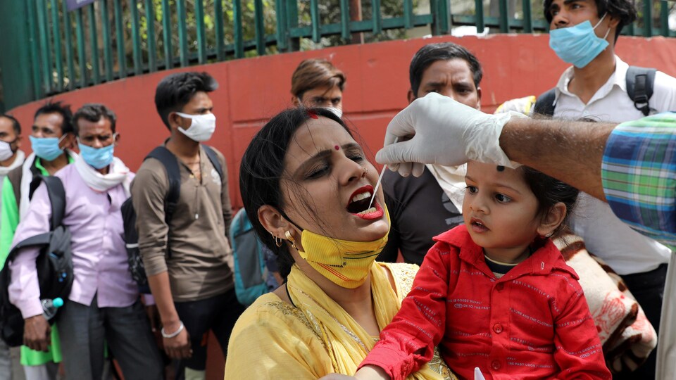 Un agent de santé recueille un échantillon sur écouvillon d'une femme dans une gare routière, à New Delhi, en Inde, le 16 mars 2021.