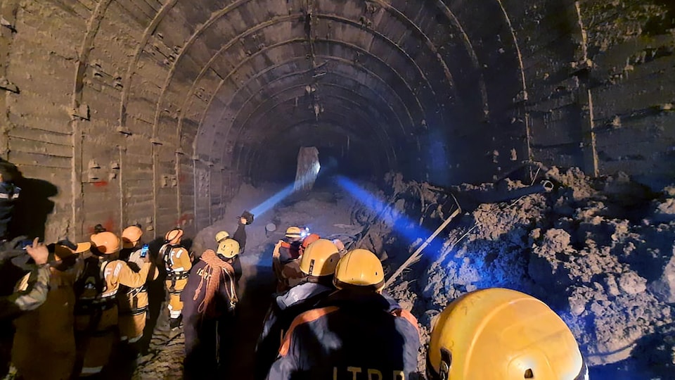 Des sauveteurs utilisent des torches pour accéder à l'intérieur d'un tunnel bloqué par la boue.
