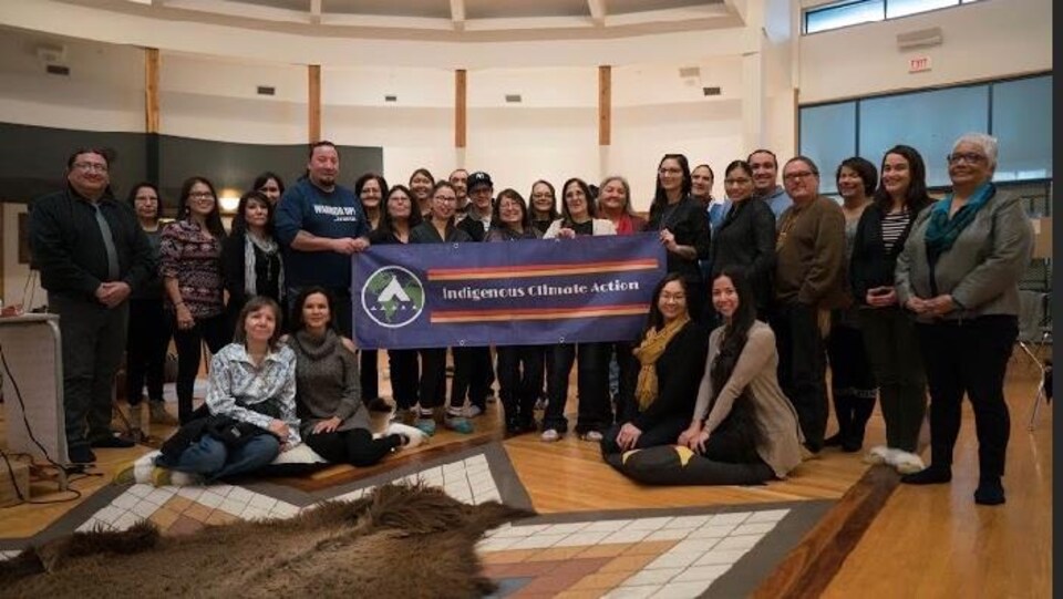 L'équipe du Indigenous Climate Action tenant une banderole à l'intérieur d'un grand local.