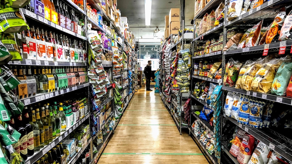 Rangée d'épicerie avec un client visible au loin, au bout de la rangée.