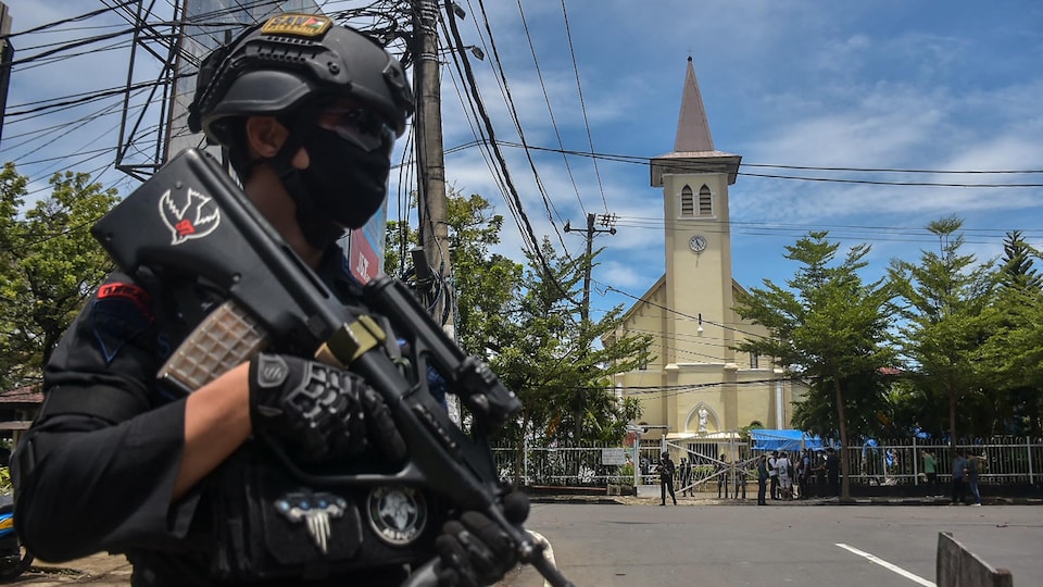 Un policier indonésien devant une église.