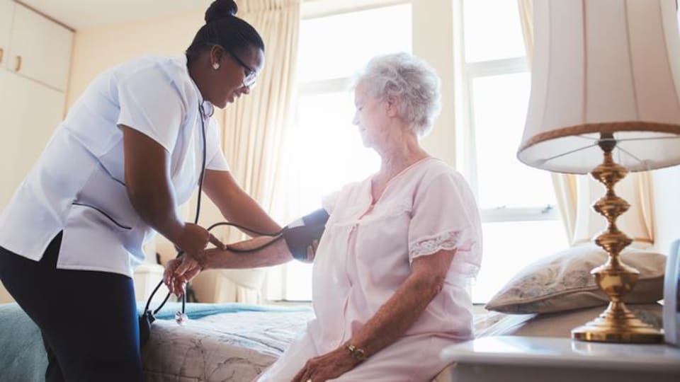 Une infirmière prend la pression d'une patiente. 