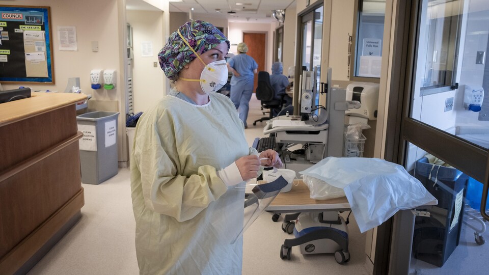 Une infirmière qui porte de l'équipement de protection se prépare à entrer dans la chambre d'un patient aux soins intensifs à l'Hôpital général de North York.