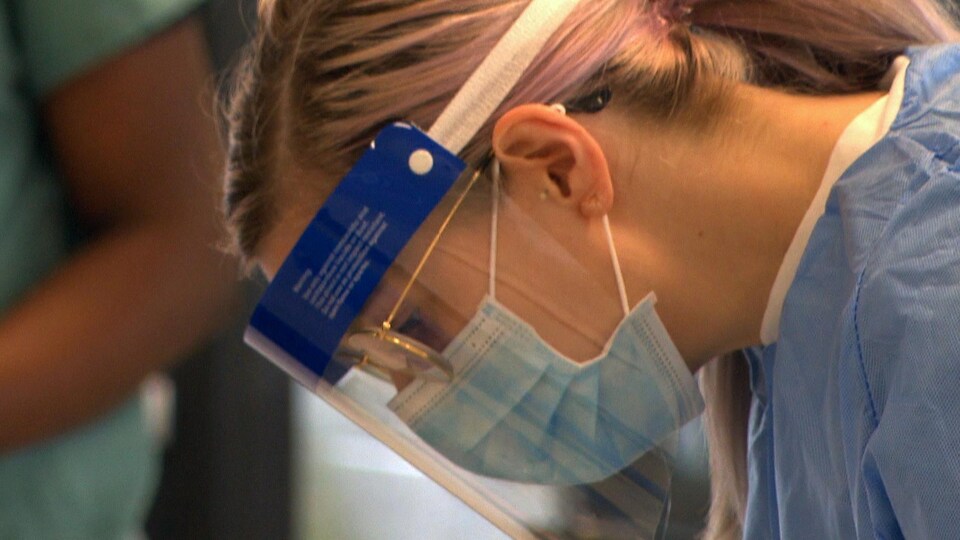 Une infirmière penche la tête vers l'avant pour discuter avec un patient.