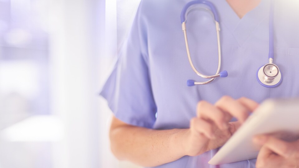 Une infirmière praticienne utilise une tablette électronique.