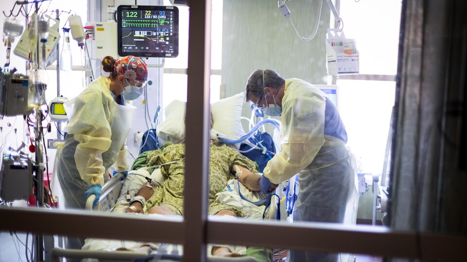 Un médecin et une infirmière s'occupent d'un patient aux soins intensifs.