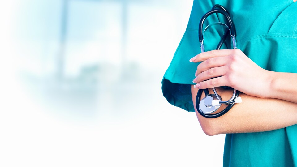 Plan serré de bras croisés avec une main qui tient un stéthoscope.