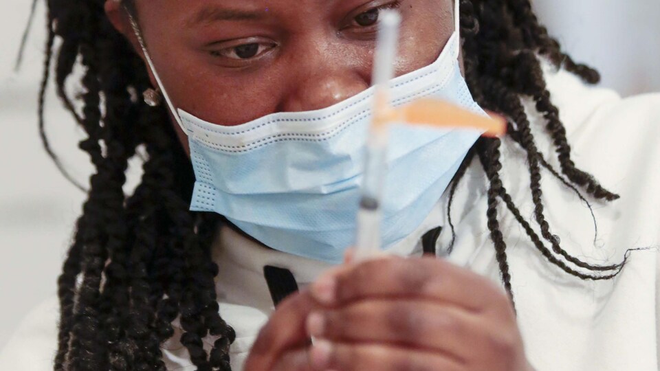 Une infirmière observe son aiguille avant la vaccination.