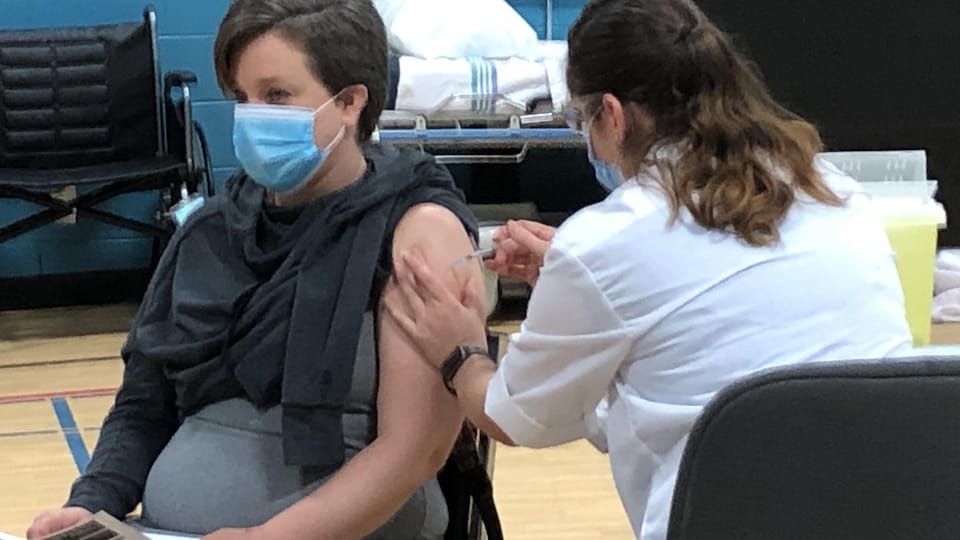 Une infirmière donne un vaccin à une femme.