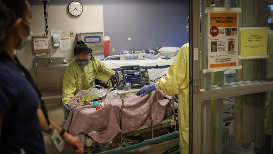 Des infirmières déplacent un patient.