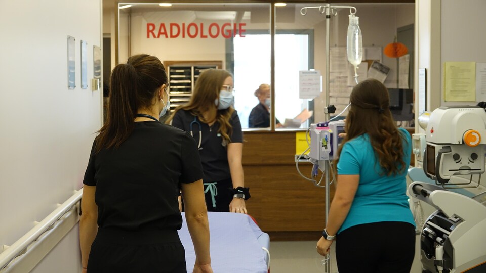 Des infirmières transportent une civière et un soluté dans le département de radiologie de l'hôpital des Îles-de-la-Madeleine.