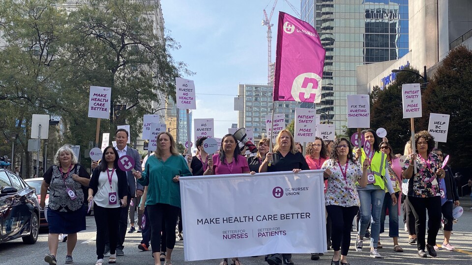 Des infirmières avec des pancartes en main et un mégaphone marchent sur la rue Burrard, à Vancouver, le mercredi 5 octobre 2022.