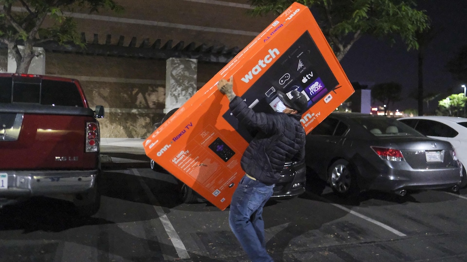 Un homme transporte un écran géant dans un stationnement.