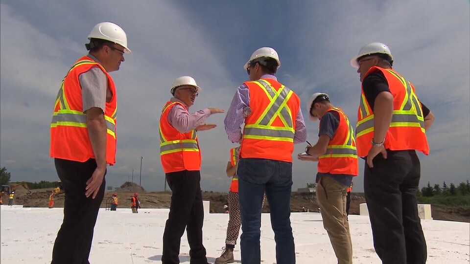 Un groupe d'ingénieurs du MTQ discutent debout sur le remblai de styromousse, sur le chantier de l'autoroute 25.