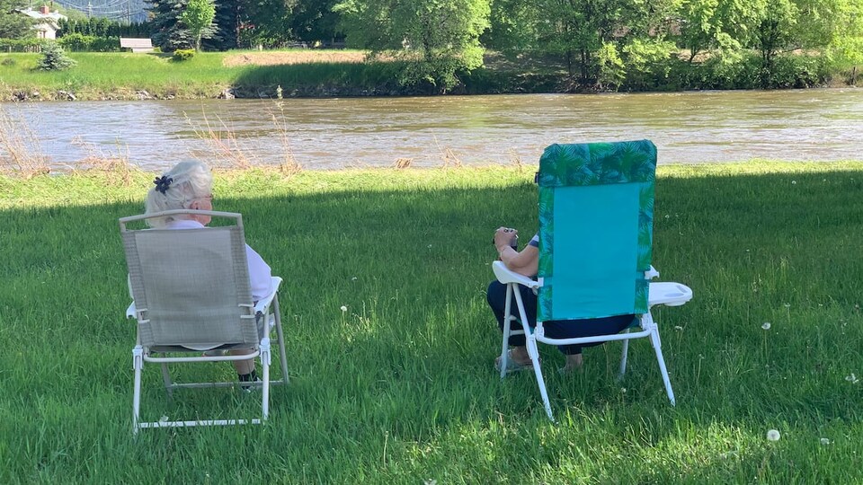 Deux personnes assises dans des chaises regardent la rivière.