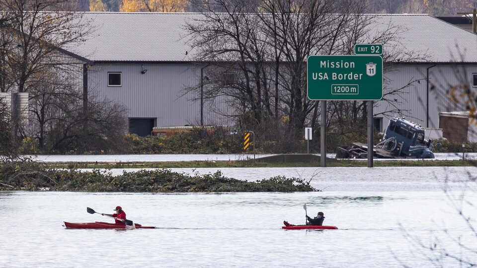 Deux personnes en kayak sur une autoroute inondée.