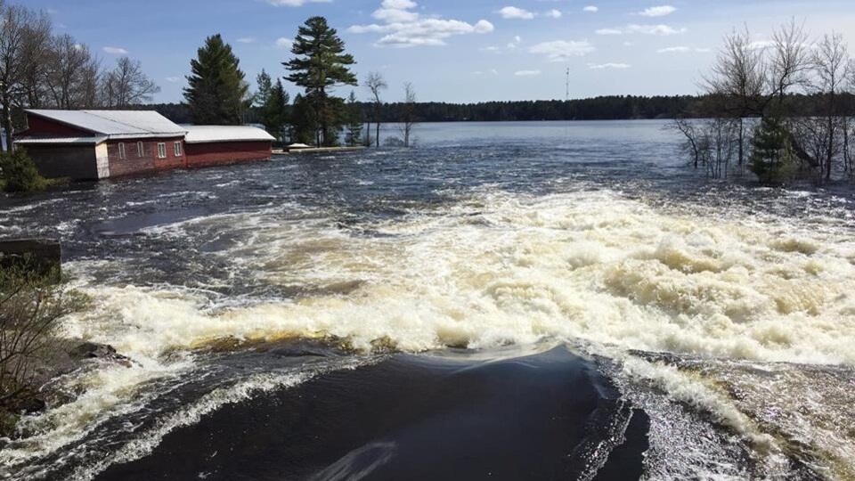 De l'eau qui s'écoule d'un barrage et un bâtiment inondé