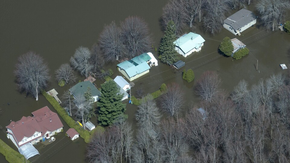 Vue aérienne de cinq maisons complètement entourées d'eau.
