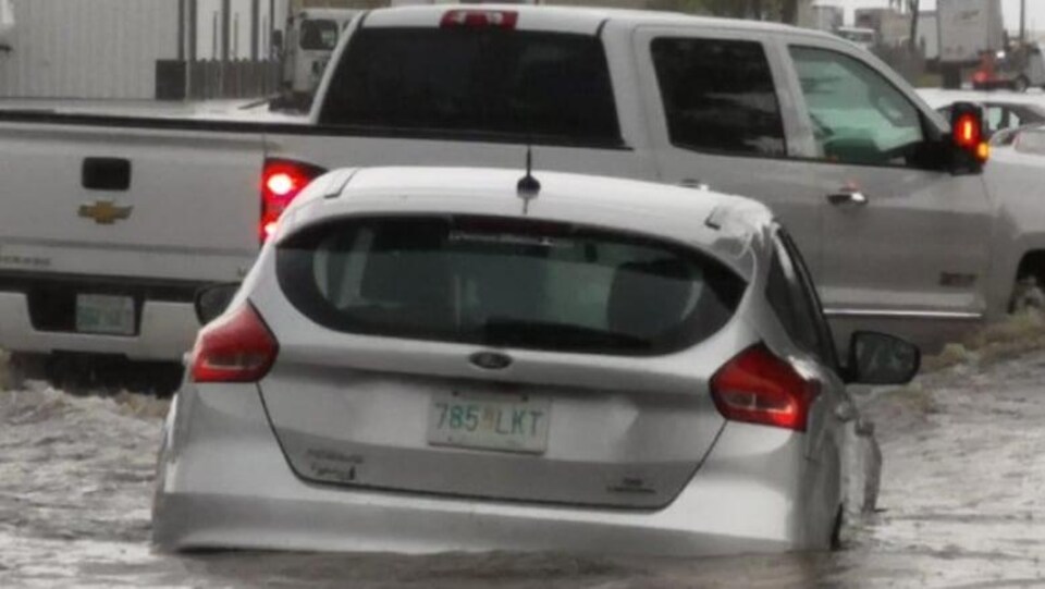 Des voitures roulent dans une rue inondée de Swift Current.