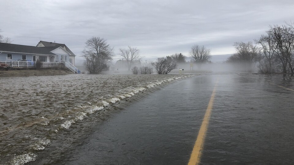 Rue inondée et vagues autour d'habitations.