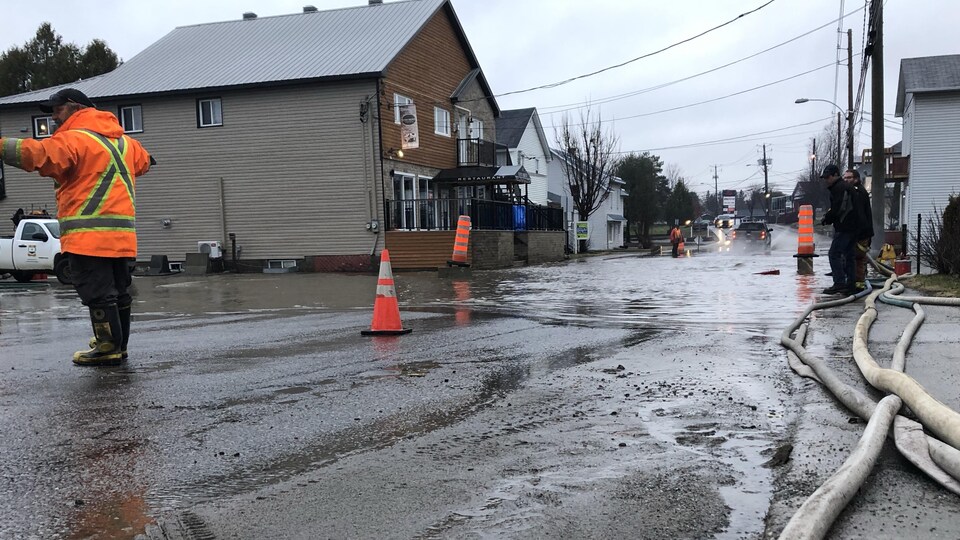 Un agent dirige la circulation dans une rue inondée du village.