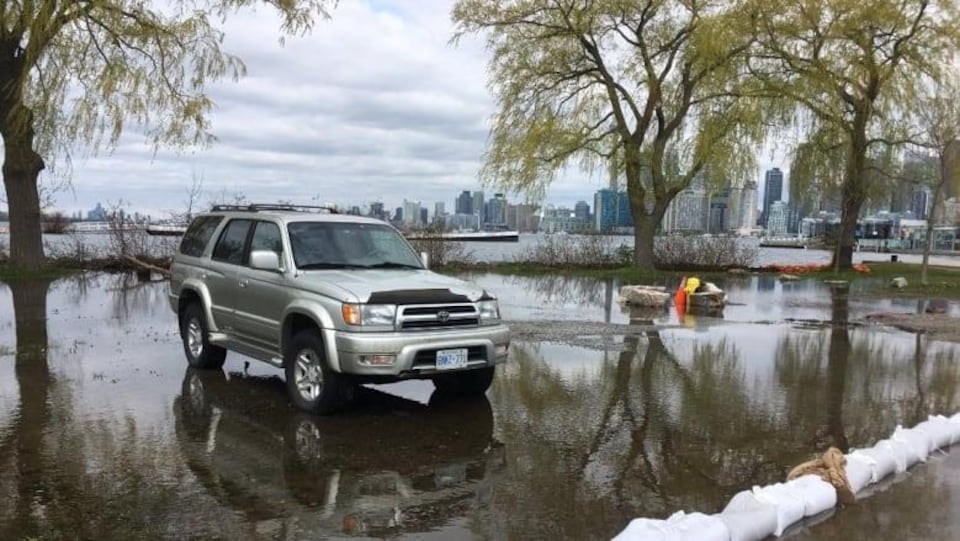 L'eau atteint un véhicule stationné près de la rive.