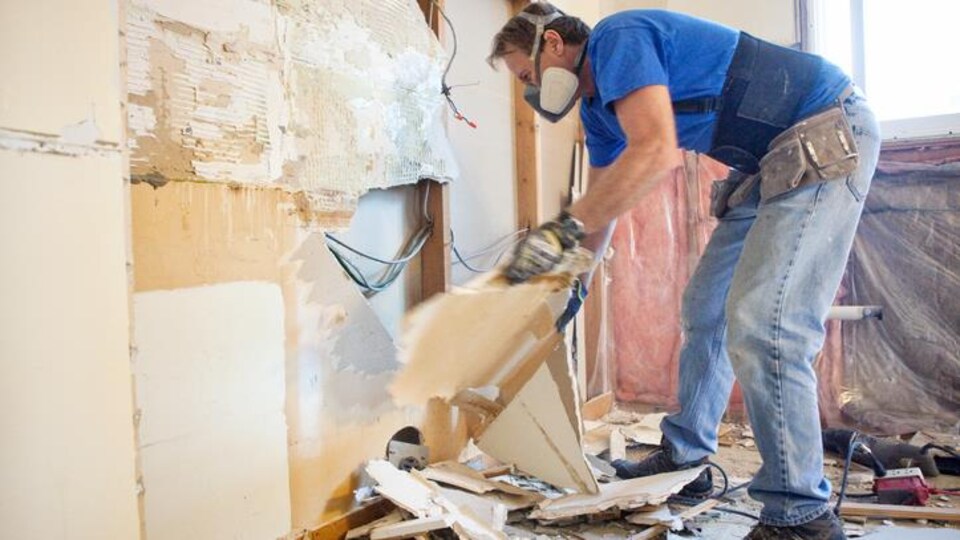 Un homme arrache un mur en contreplaqué.